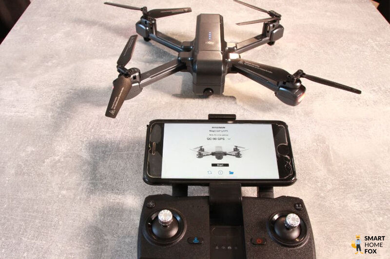 Die Maginon QC 90 Mini Drohne liegt auf dem Tisch und ist mit der App auf dem Smartphone verbunden